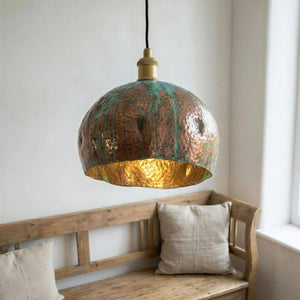 Copper pendant light hanging above a wooden bench with pillows in a room.