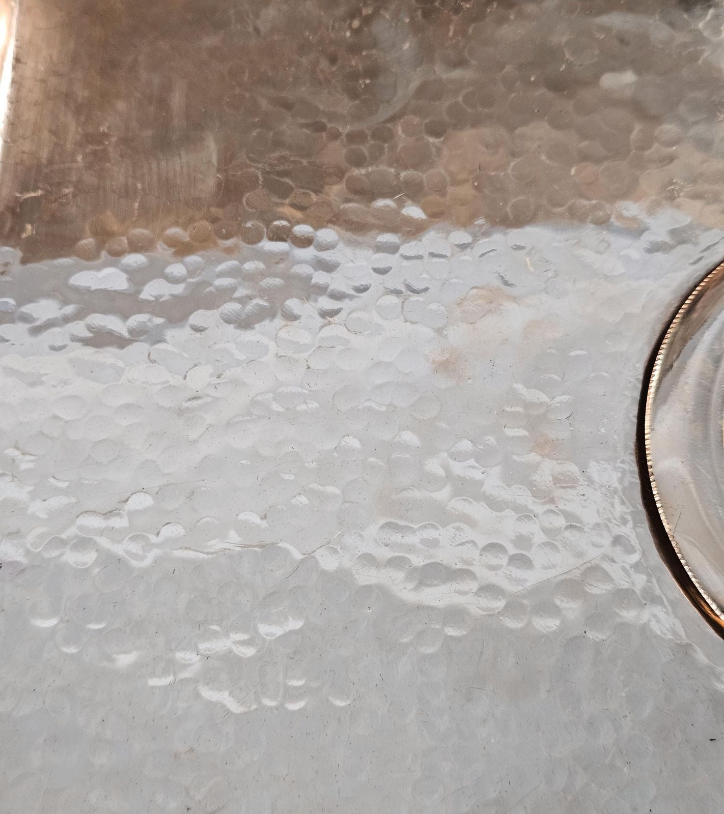 Close-up of a metallic surface with water droplets and a blurred background