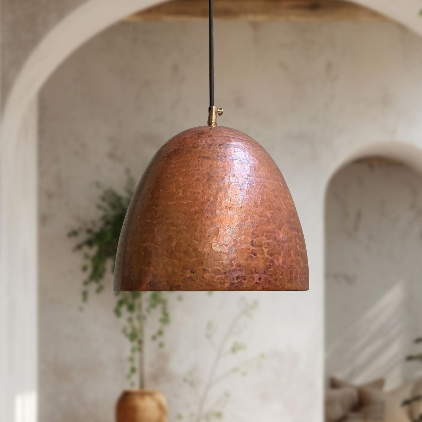 Copper pendant light hanging in a room with arches and plants