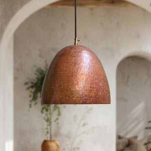 Copper pendant light hanging in a room with arches and plants