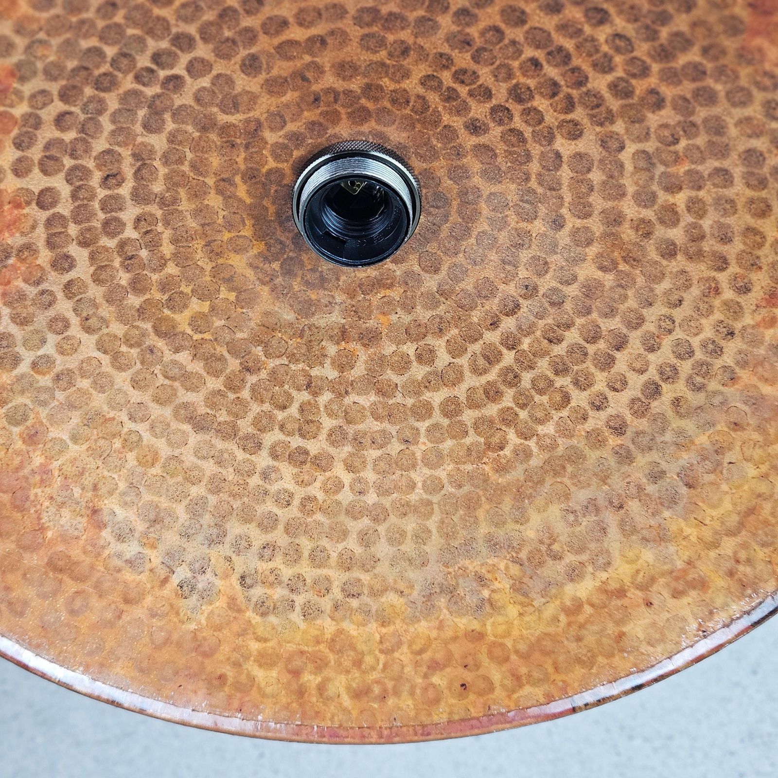 Rust-patterned metal surface with a central drain hole on a light gray background