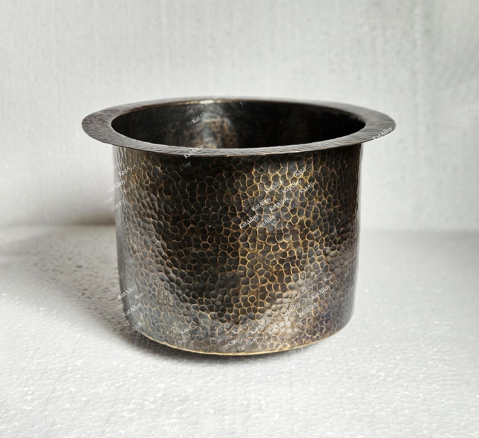 Hammered metal pot on a textured white background