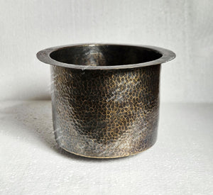 Hammered metal pot on a textured white background