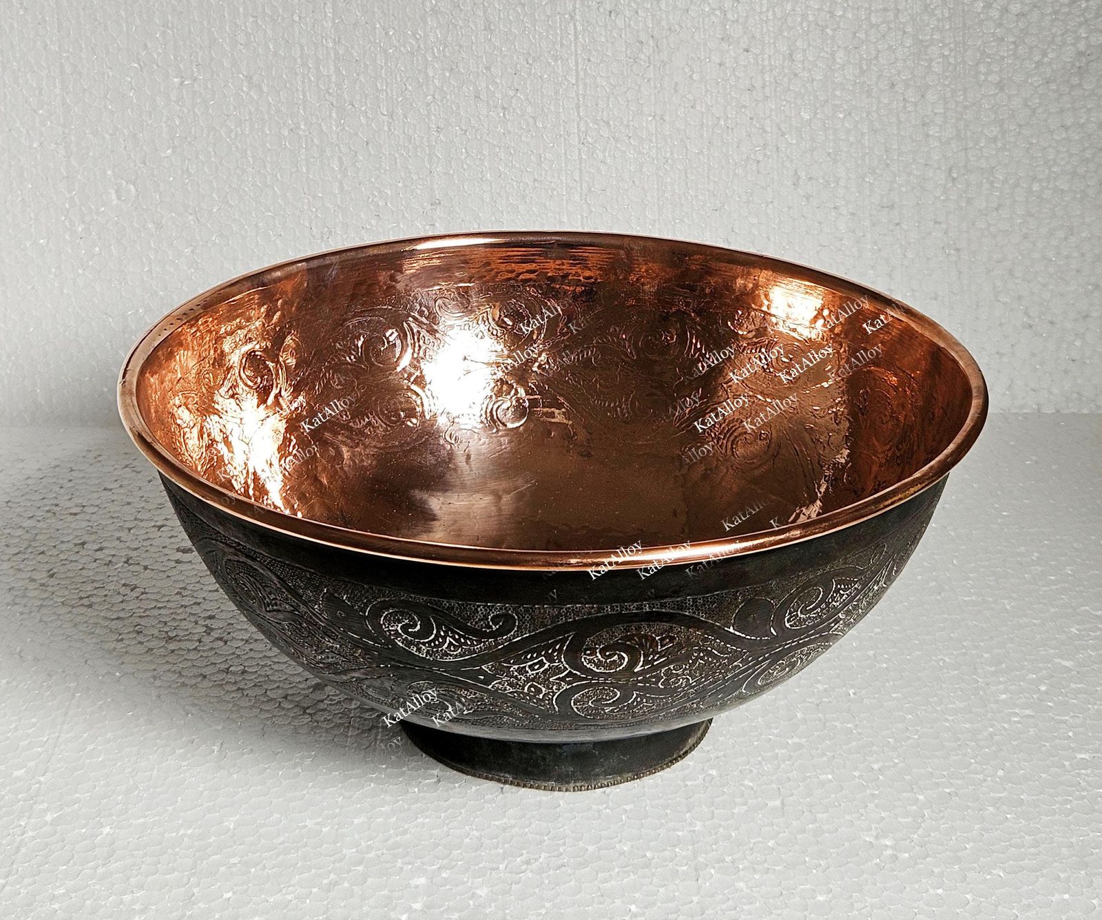 Copper bowl with embossed design on a light gray background