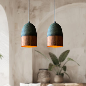 Two pendant lights with green top and wooden bottom in a room with plants and a textured wall.