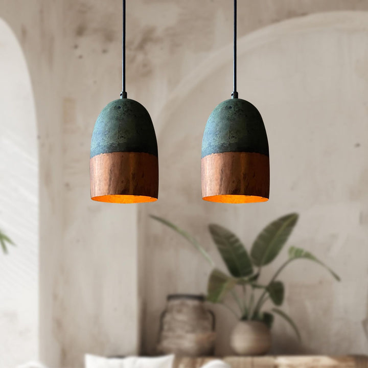 Two pendant lights with green top and wooden bottom in a room with plants and a textured wall.