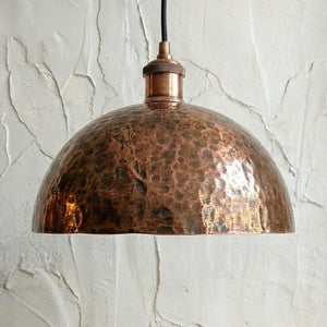 Copper pendant light against a textured white wall