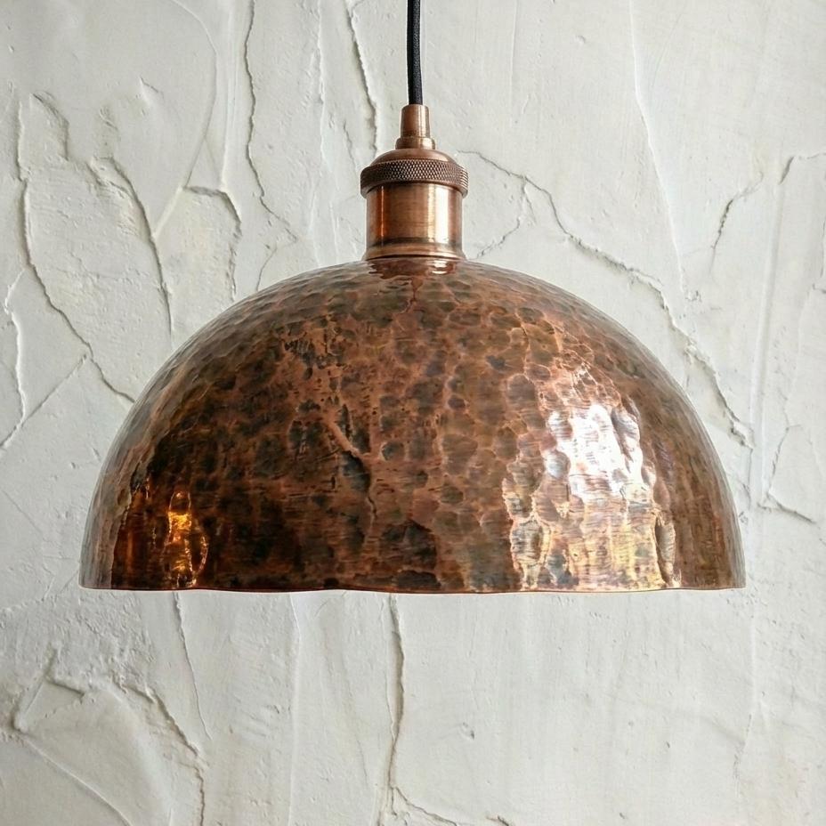 Copper pendant light against a textured white wall