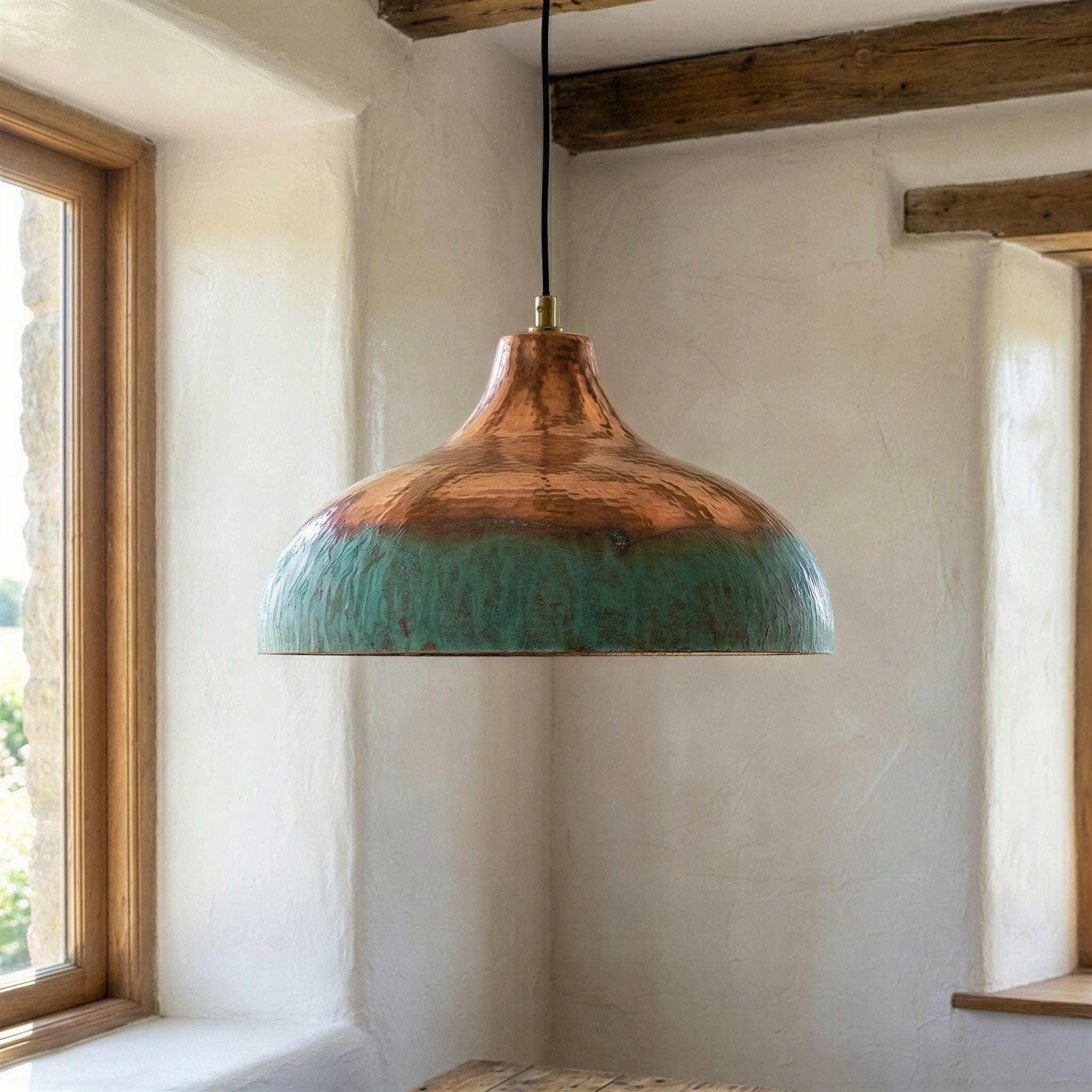 Pendant light with copper and turquoise design hanging in a room with wooden beams and a window.