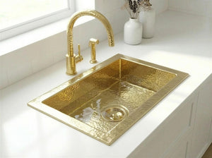 Gold kitchen sink with faucet on a white countertop