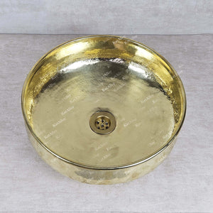 Gold-colored round basin with central drain on a gray background