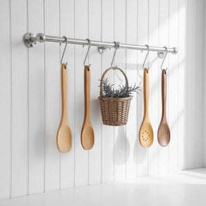 Wooden spoons and a basket hanging on a rack against a white wooden panel background