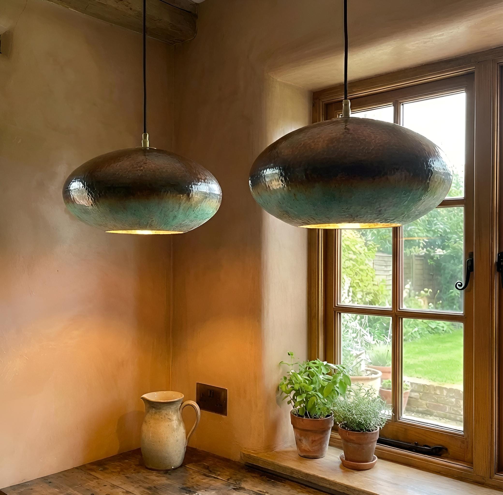 Two hanging pendant lights in a room with a window and plants.