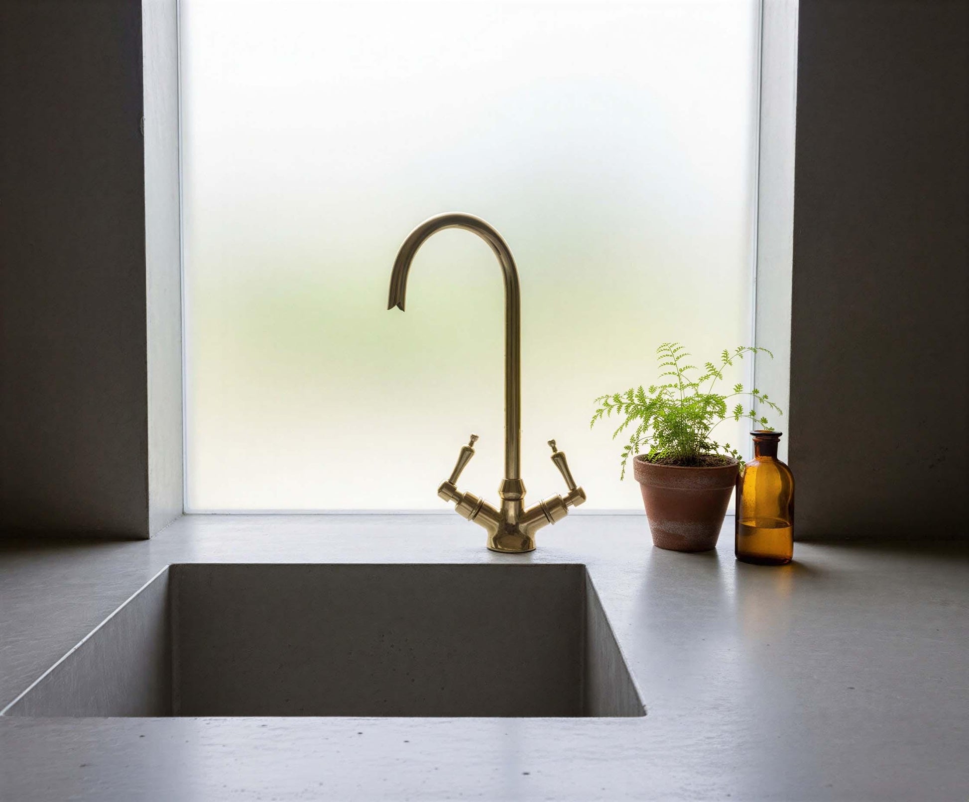 Modern kitchen sink with brass faucet and decorative elements.