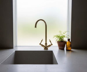 Modern kitchen sink with brass faucet and decorative elements.