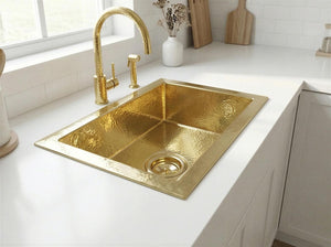 Gold kitchen sink with faucet on a white countertop