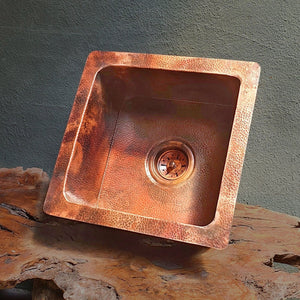 Copper sink on a wooden surface with a gray background