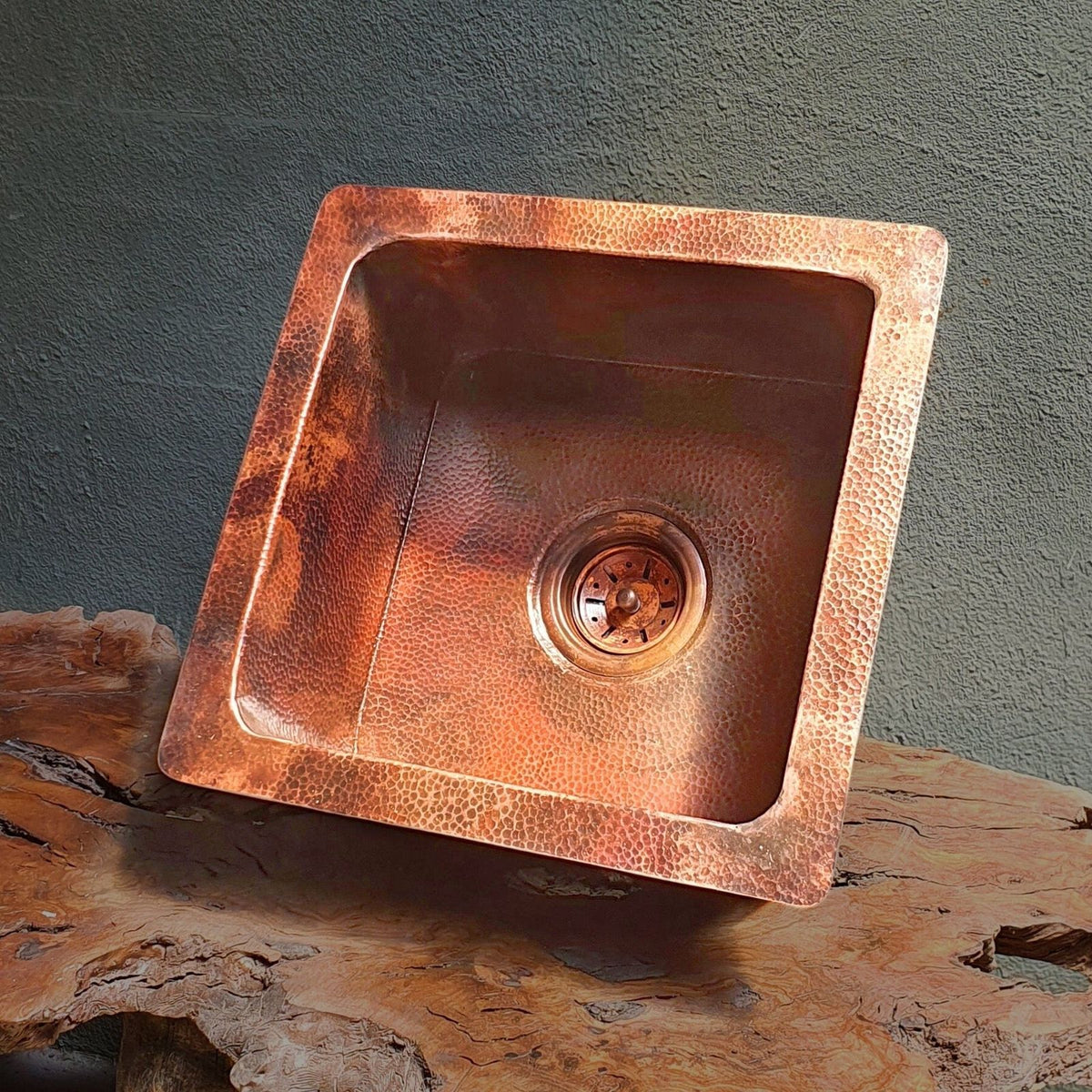 Copper sink on a wooden surface with a gray background