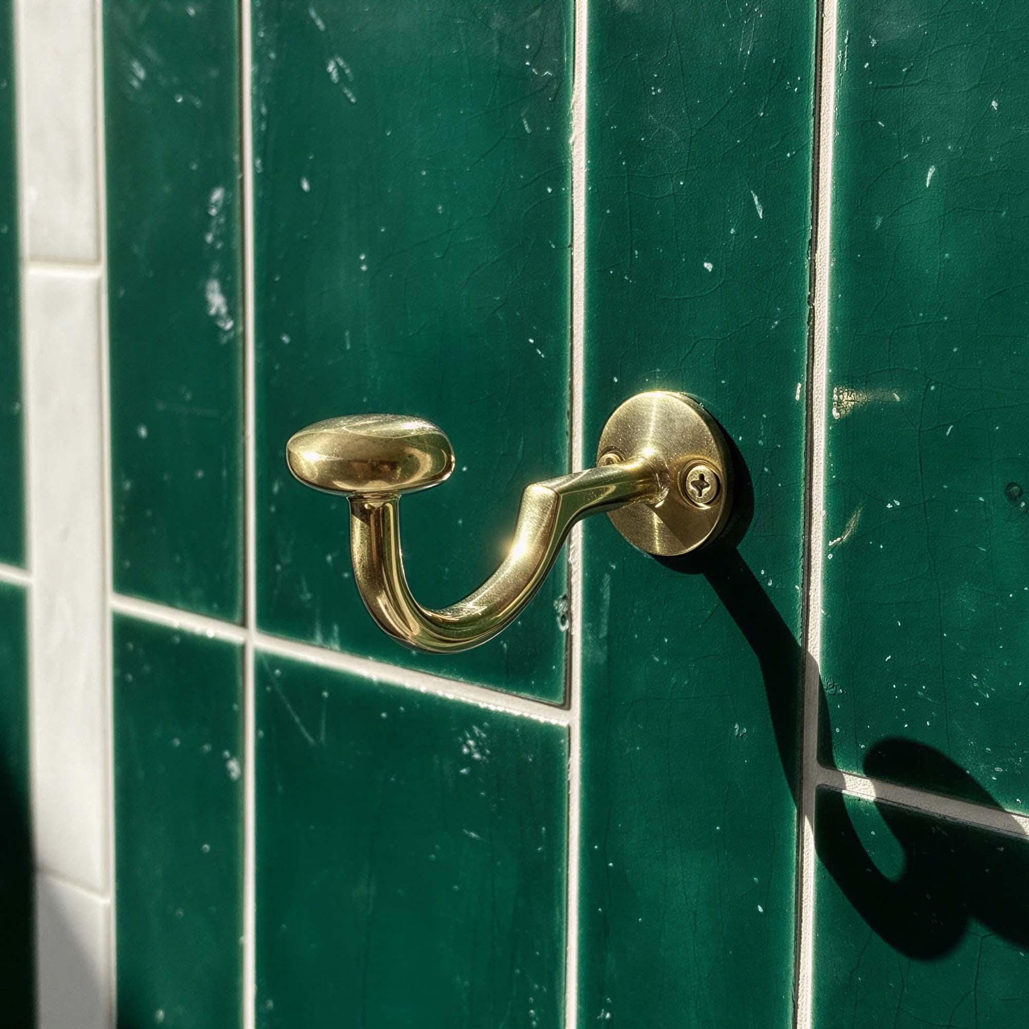 Gold door handle on a green tiled door
