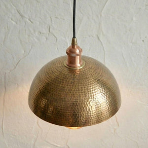 Hammered brass pendant light against a textured white wall