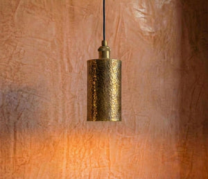 Gold pendant light hanging against a textured brown wall