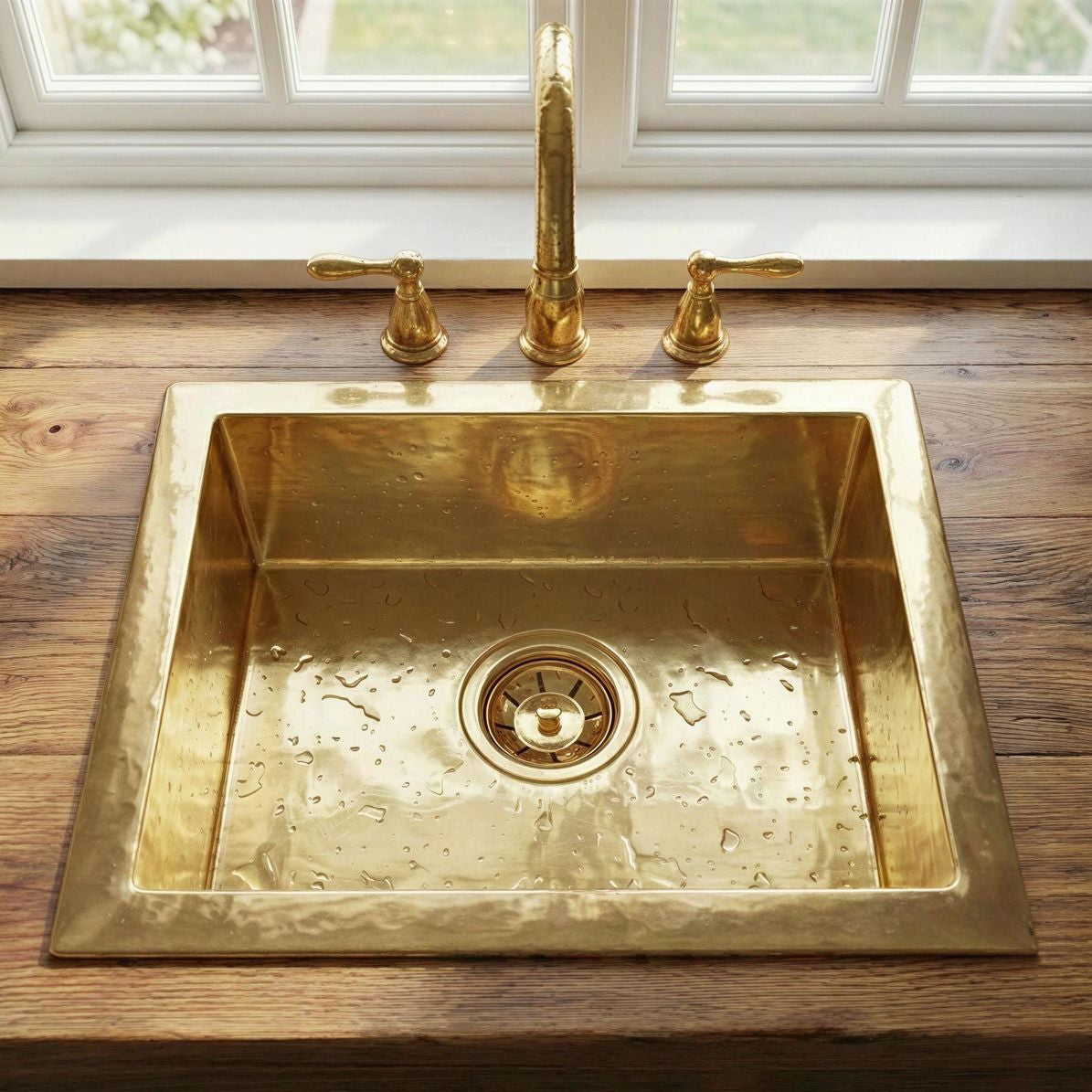 Brass kitchen sink with faucet on a wooden countertop