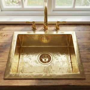 Brass kitchen sink with faucet on a wooden countertop