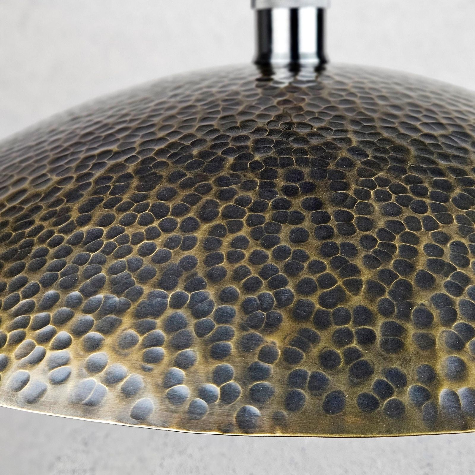 Close-up of a textured metallic lampshade on a light gray background