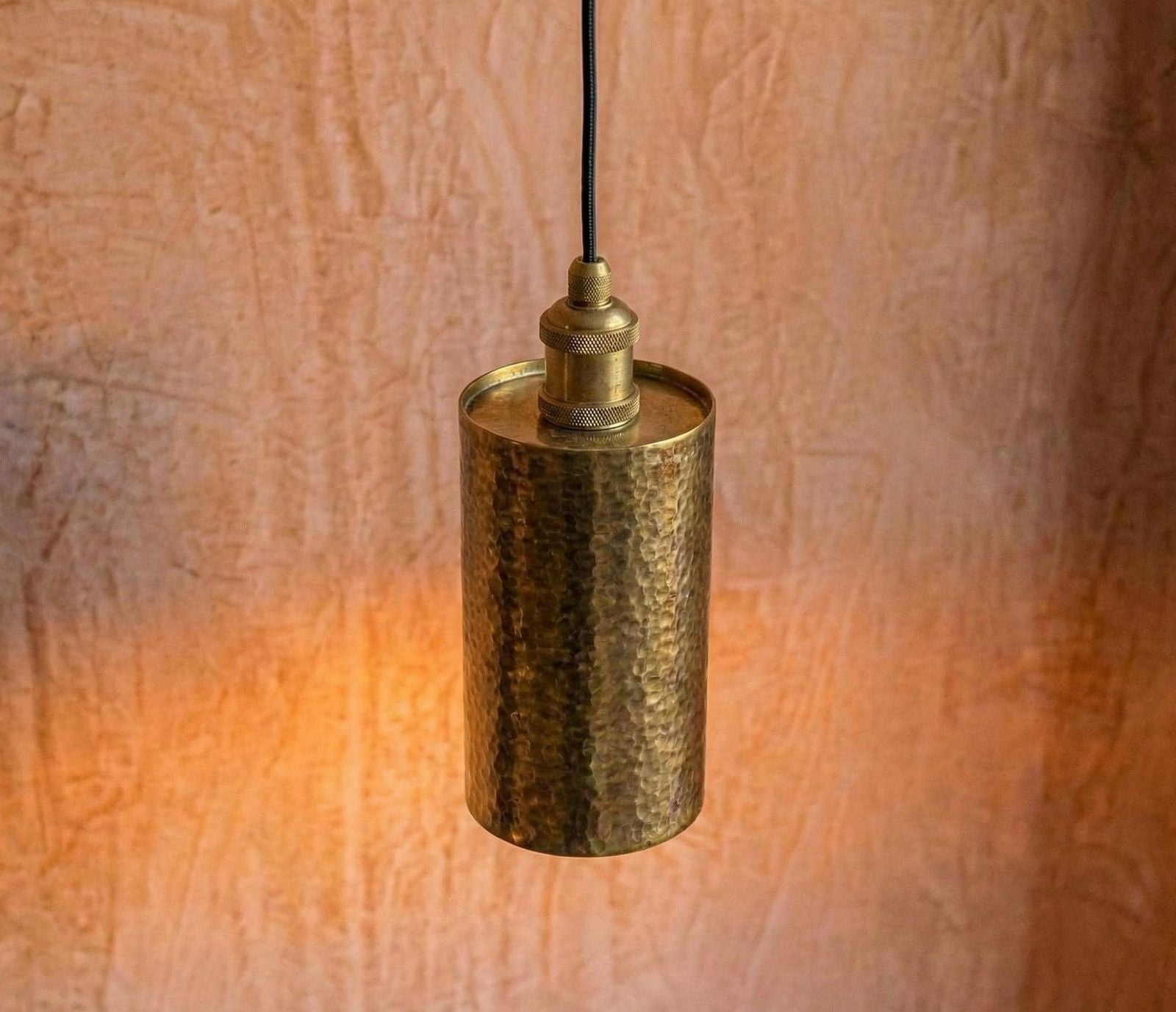Brass pendant light against a textured wall