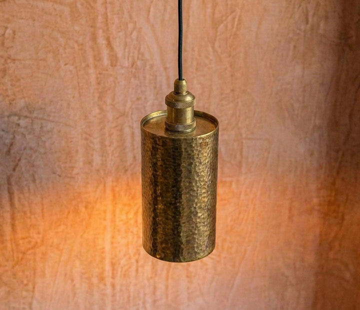 Brass pendant light against a textured wall