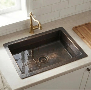 Brass Bronze kitchen sink with gold faucet on a light countertop