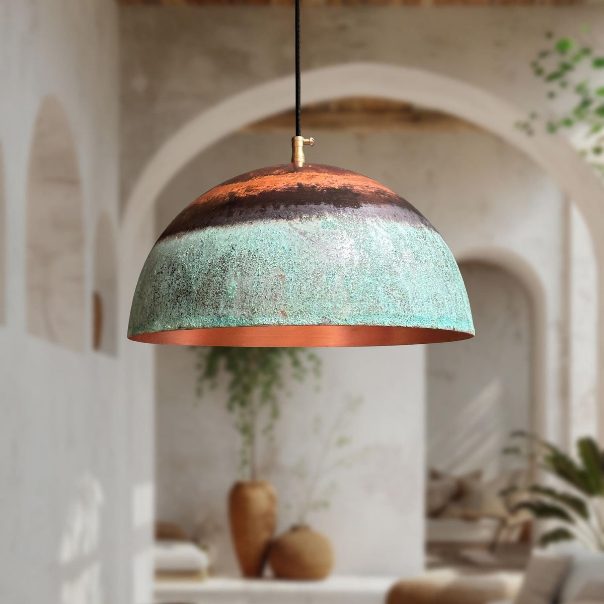 Decorative pendant light with a textured design hanging in a room with plants and arches.