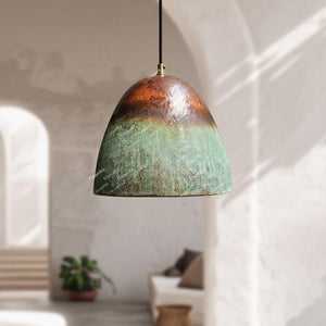 Decorative pendant light with a green and brown gradient shade in a softly lit room.