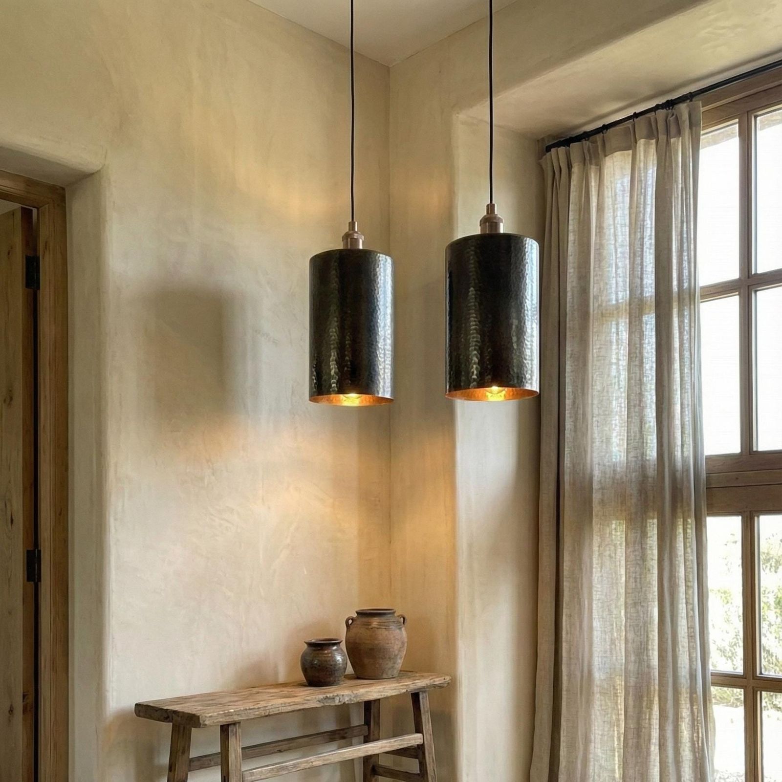 Two pendant lights hanging in a room with a wooden table and window.