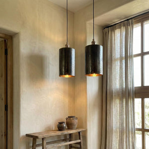 Two pendant lights hanging in a room with a wooden table and window.