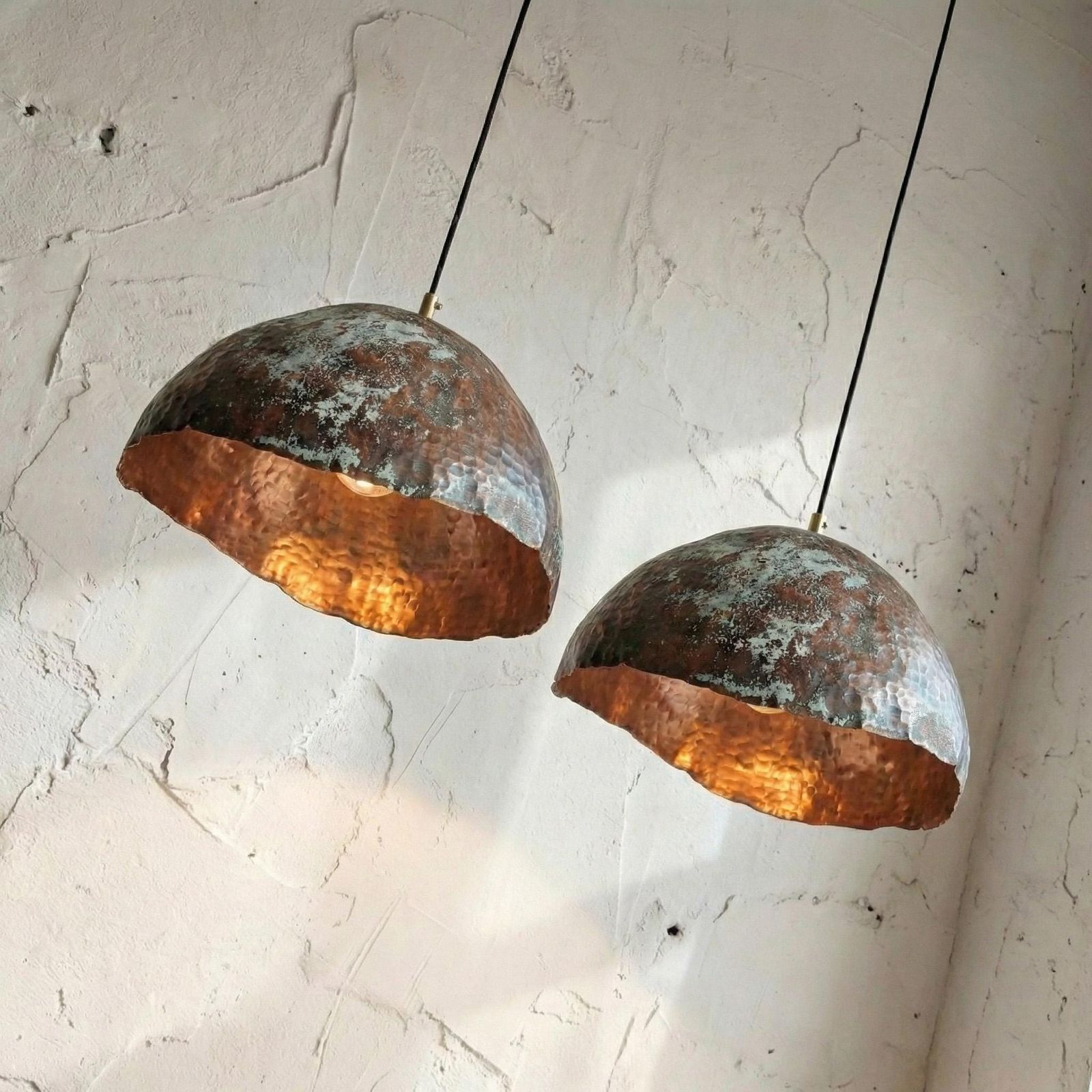 Two rustic pendant lights hanging against a textured white wall.