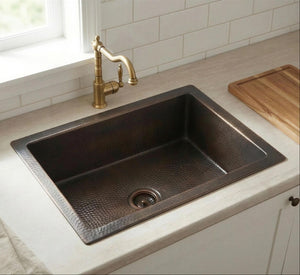 Copper kitchen sink with brass faucet in a modern kitchen setting