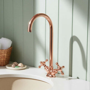 Rose gold faucet on a white sink against a light green paneled wall.
