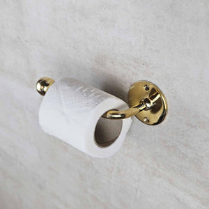 Gold toilet paper holder with a roll of toilet paper on a white marble surface