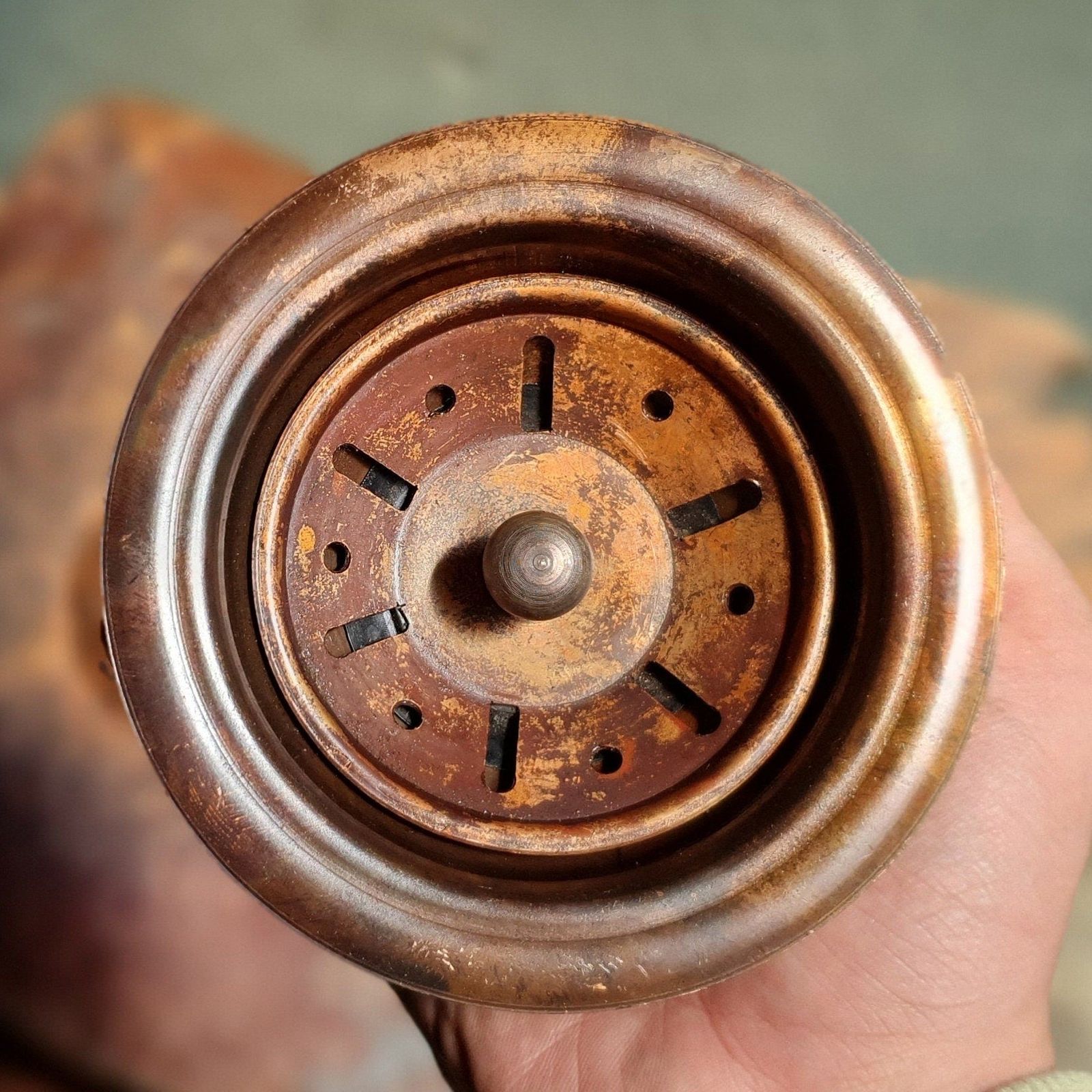 Rust-covered metal object held in a hand with a blurred background