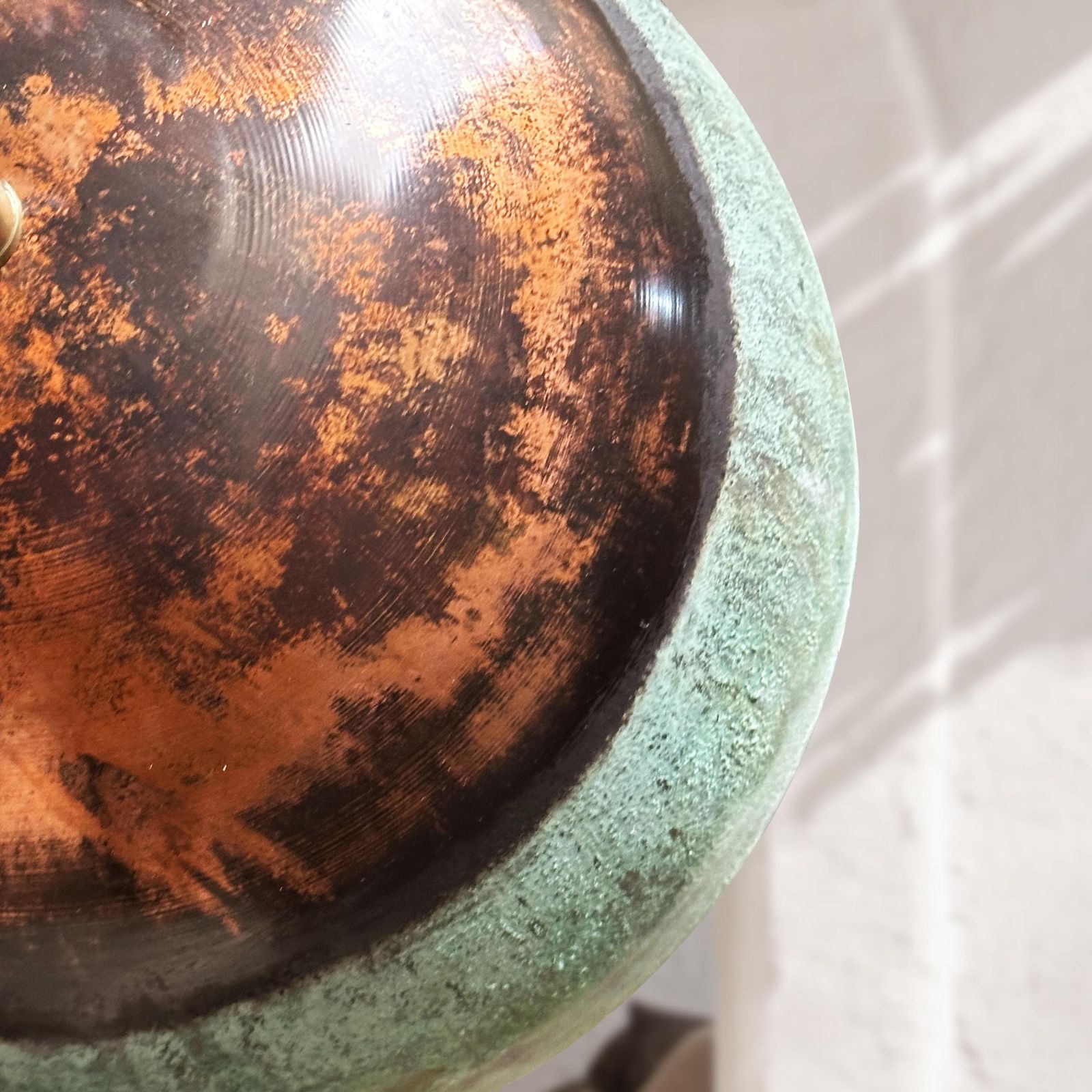 Close-up of a textured metal object with a copper-like finish on a white background