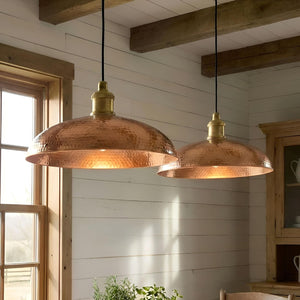 Two copper pendant lights hanging in a room with wooden beams and a window.