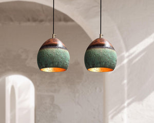 Two hanging ceramic lamps with green and gold finish on a neutral background