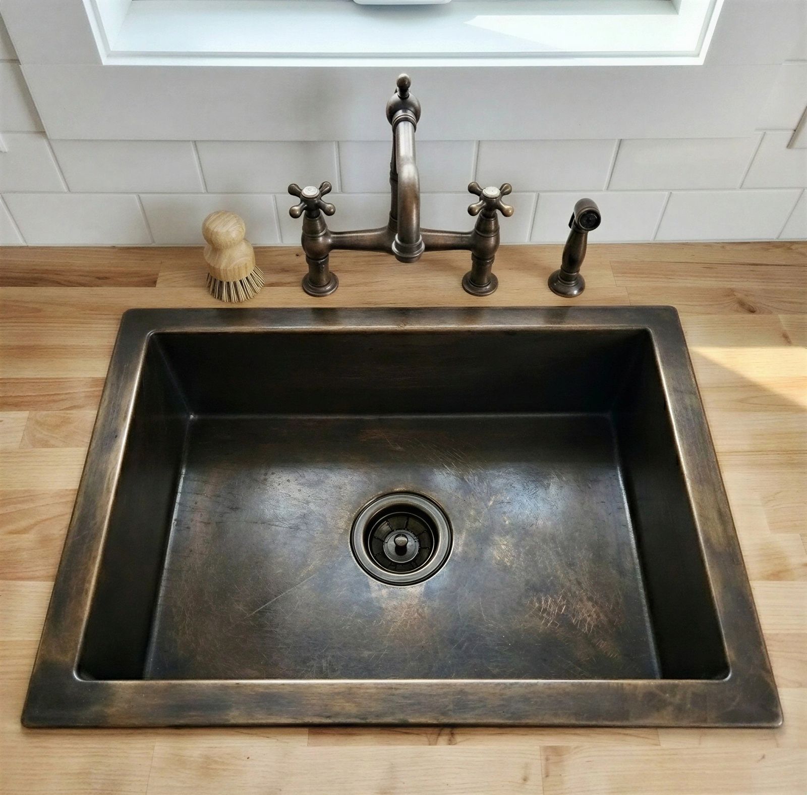 Bronze kitchen sink with faucet on a wooden countertop
