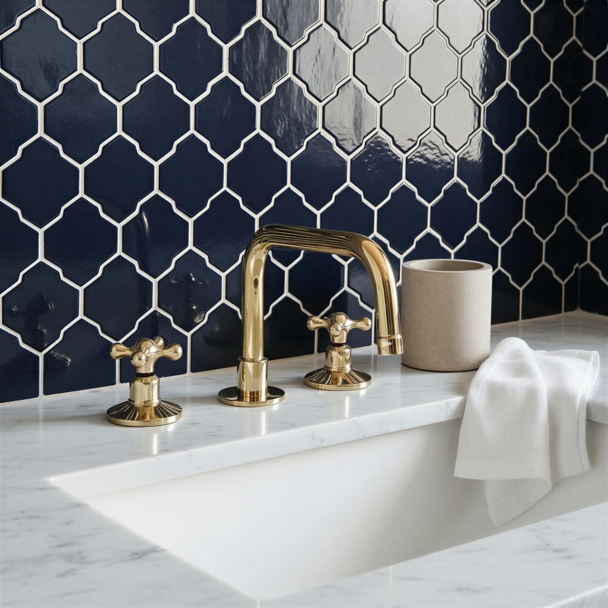 Bathroom with gold faucet and fixtures against a dark blue tiled wall.