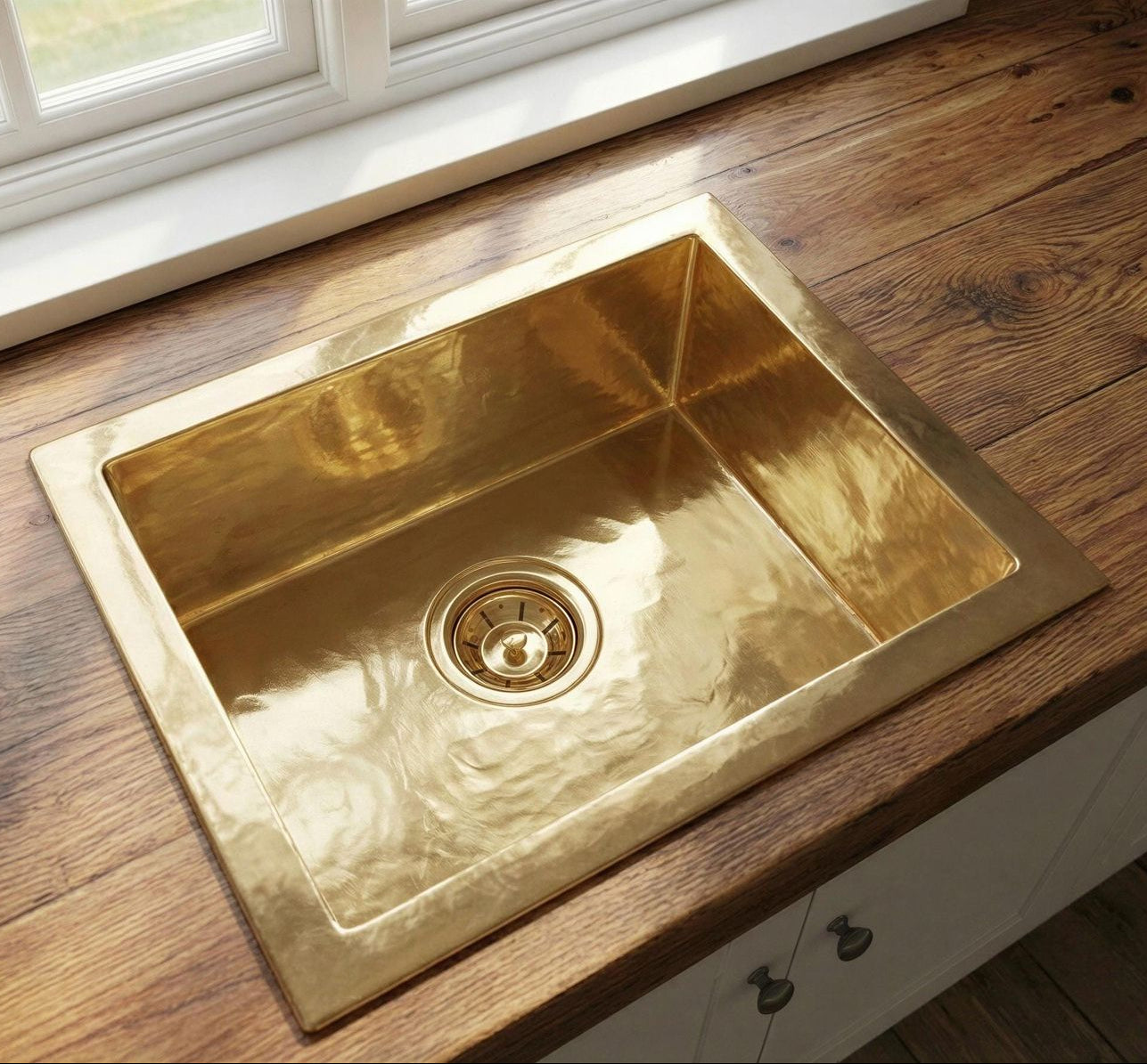 Gold kitchen sink on a wooden countertop with a window in the background