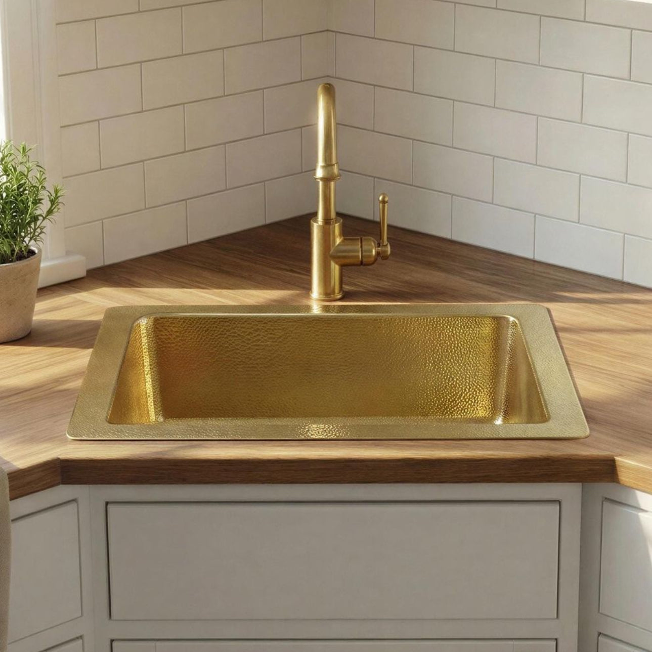 Gold kitchen sink in a modern kitchen with wooden countertops and white cabinets.