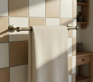 Beige towel hanging on a gold towel rack against a tiled wall.