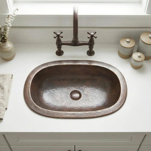 Brass sink with bronze faucet on a white countertop
