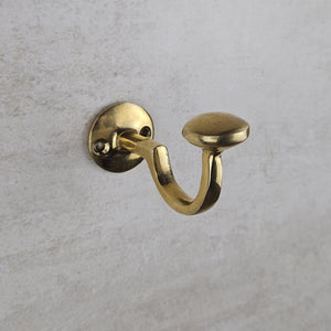 Brass wall hook on a textured gray background